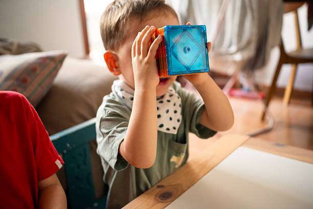 A young child holds colorful magnetic tiles