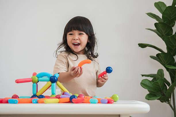 toddler girl playing colorful magnetic tiles