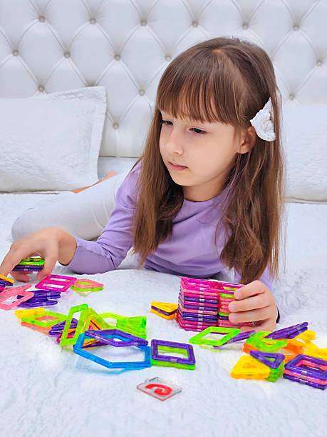 toddler girl playing colorful magnetic tiles