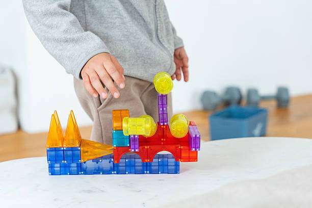 Young child engaged in imaginative play with a set of colorful magnetic-tiles building blocks