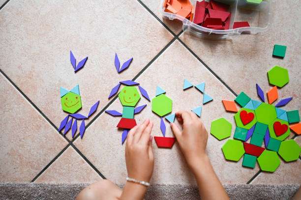 Caucasian baby girl wearing a pajamas, builds with magnetic tiles
