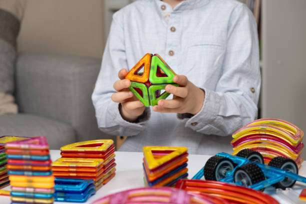 A child plays with a magnetic tiles construction set. Interesting educational toys