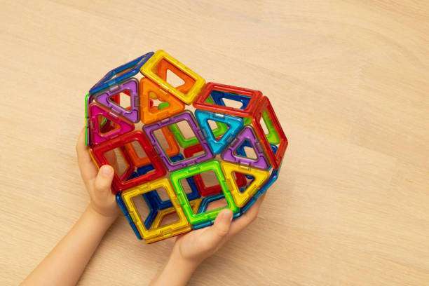 A child plays with a magnetic tiles construction set. Interesting educational toys