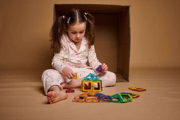 Caucasian baby girl wearing a pajamas, builds with magnetic tiles