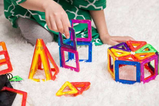 Little girl playing at home with interactive magnet toys. Lleisure games.magnetic tiles