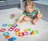 Caucasian baby girl wearing pajamas builds with magnetic tiles