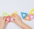 A young child holds colorful magnetic tiles