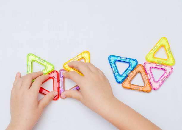 A young child holds colorful magnetic tiles