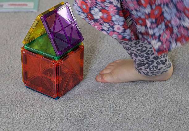 toddler girl playing colorful magnetic tiles